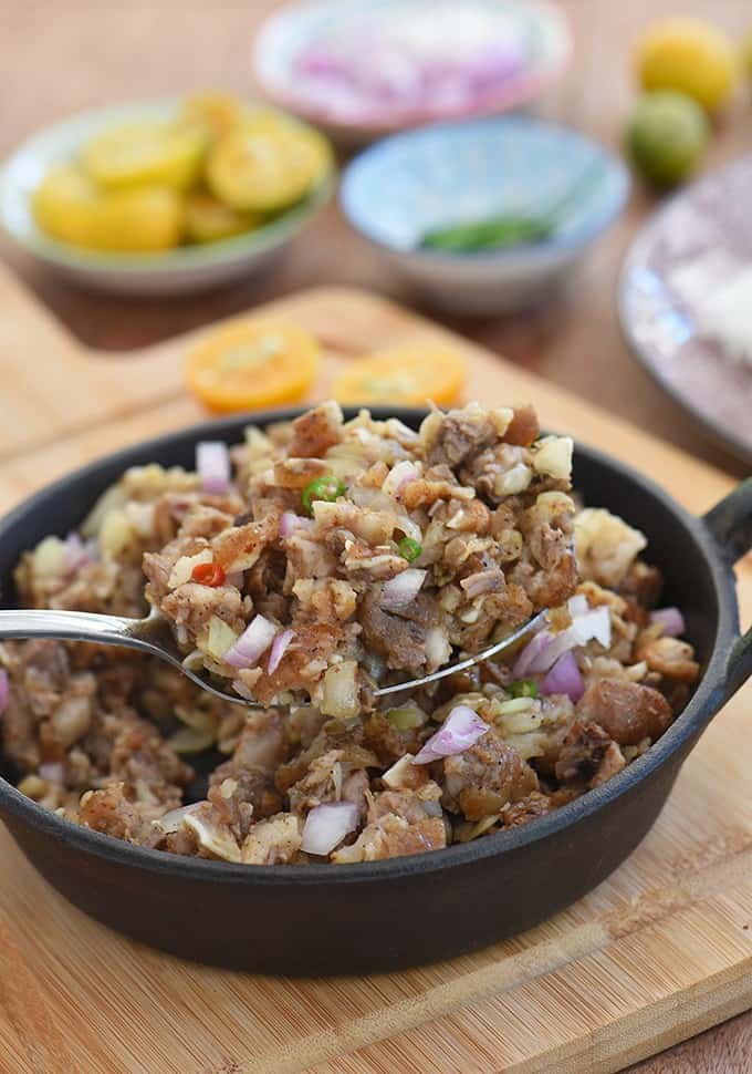 供应Kapampangan Pork Sisig，从铸铁煎锅中使用大勺子gydF4y2Ba