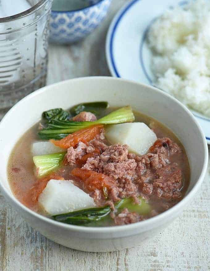 Sinigang Na康复牛肉在一个白色碗的牛肉与米板材在边gydF4y2Ba